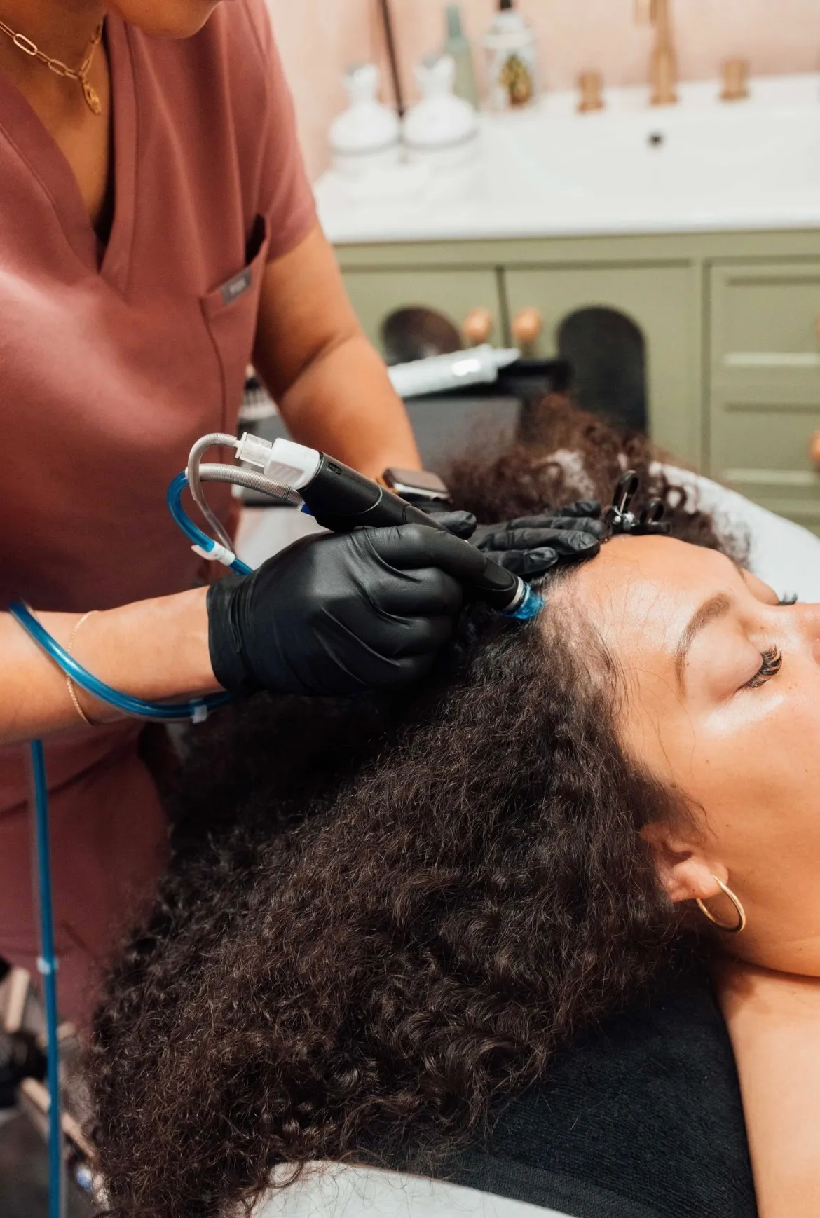 HydraFacial Keravive scalp treatment device working through sectioned hair at the scalp